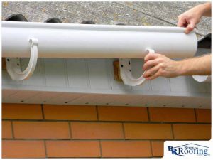 a technician installing gutters on home