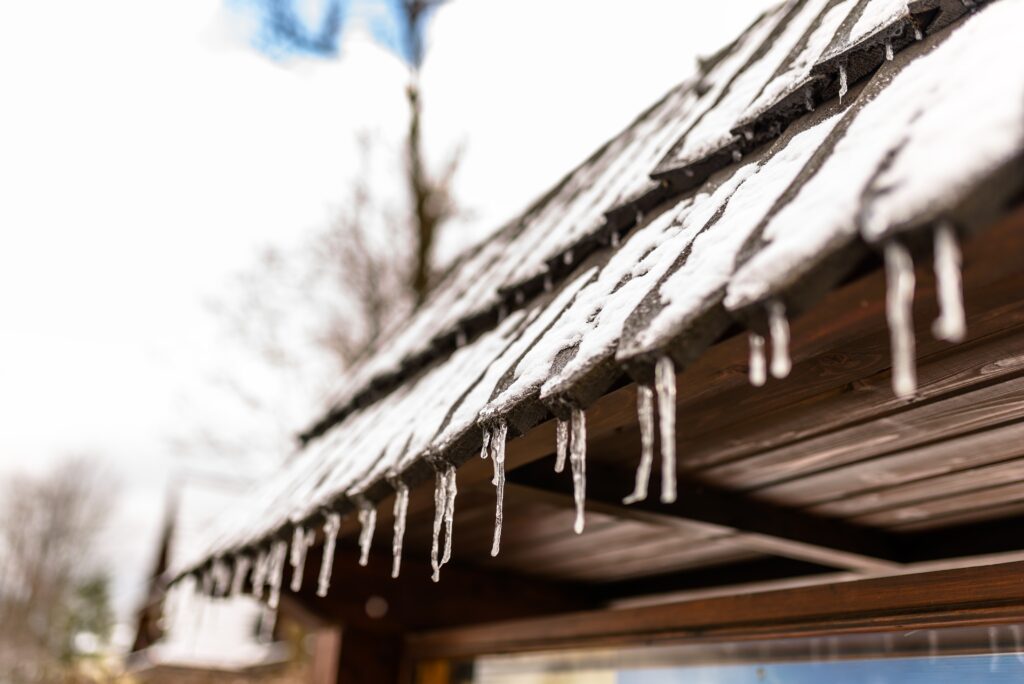 berry-roofing-solar-hanging-icicles-from-the-roof-of-a-wooden-building-Winter-Roof-Maintenance-During-the-Coldest-Months
