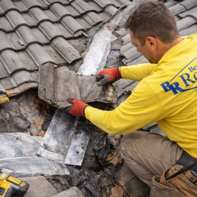 Emergency concrete tile roof leak repair in Riverside, California showing technician removing tiles to repair damaged underlayment and flashing